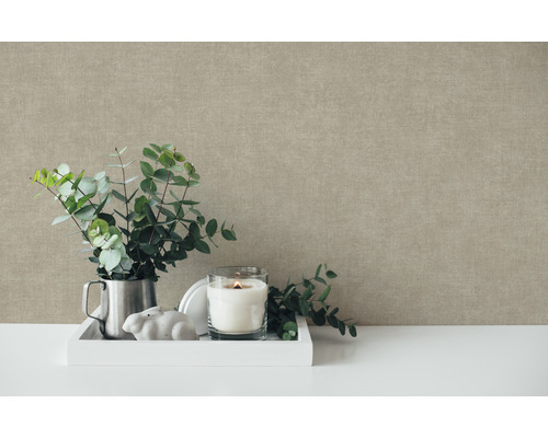 Dekorative Stillleben-Szene mit Eukalyptuszweigen, Kerze und Zierelementen vor einer strukturierten Wand