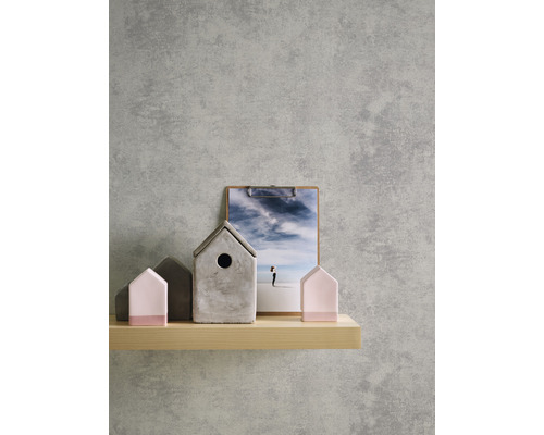 Dekorative Häuser aus Beton und Holz auf einem Regal vor einer grauen Wand.