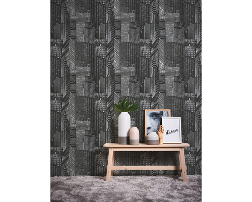 Zimmer mit einer Tapete mit einem Wolkenkratzer-Muster hinter einem Holztisch