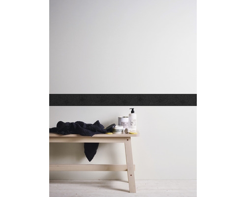 Dekorative Wand mit Bordüre, Handtuch und Pflegeprodukten auf einer Holzbank