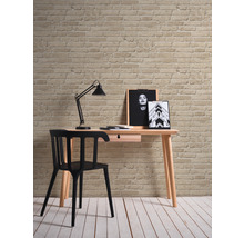Schreibtisch mit Stuhl, Lampe und Dekoration vor einer Ziegelwand