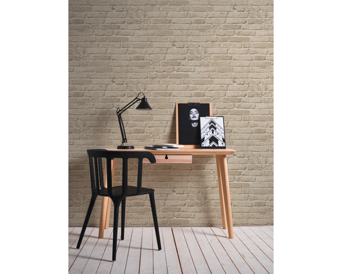Schreibtisch mit Stuhl, Lampe und Dekoration vor einer Ziegelwand