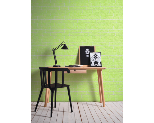 Ein Arbeitszimmer mit einem Schreibtisch, einem Stuhl und einer Lampe vor einer Wand mit Ziegelmuster