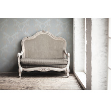 Dekoratives Sofa vor einer floral gemusterten Tapete
