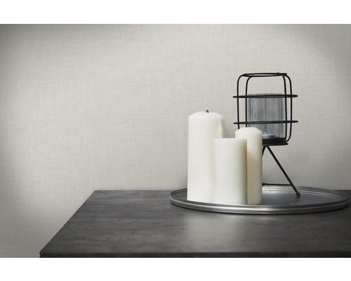 Dekorative Szene mit Leinwandtapete, Kerzen und Laterne auf einem Tisch.