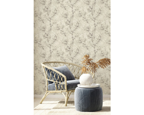 Szene mit Rattansessel, Hocker und Tapete mit Pflanzenmuster für ein stilvolles Interieur