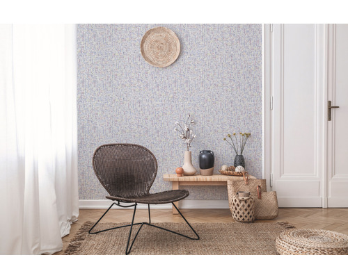 Wohnraum mit gemusterter Tapete, Rattansessel und Holzboden
