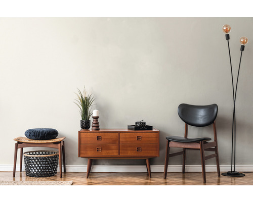 Wohnzimmer mit Kommode, Stuhl, Hocker, Stehlampe und dekorativen Gegenständen