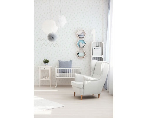 Hell eingerichtetes Kinderzimmer mit Gitterbett, Sessel und Dekoration