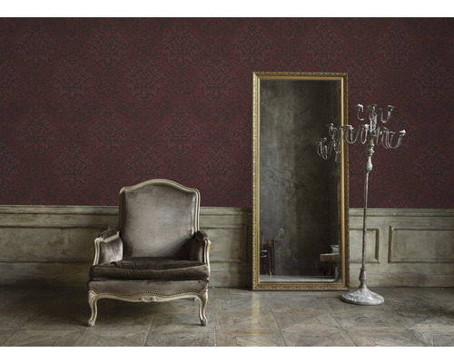 Innenraum mit Sessel, Spiegel und ornamentaler Tapete für eine wohnliche Atmosphäre.