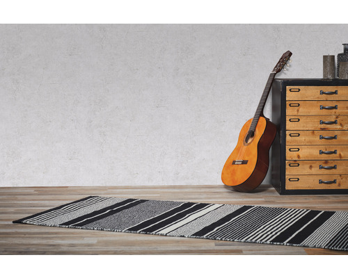 Ein Zimmer mit einem gestreiften Teppich, einer Gitarre und einer Kommode.