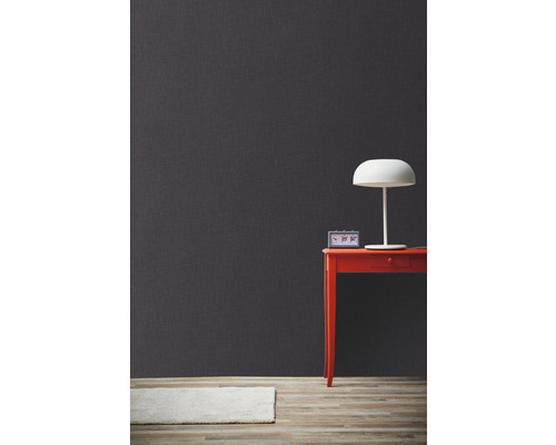 Dekorative graue Wand mit Tisch, Lampe und Teppich für ein modernes Wohnambiente.