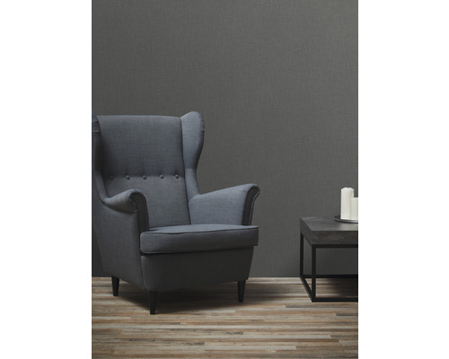 Wohnzimmer mit Sessel, kleinem Tisch und drei Kerzen