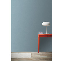 Szene mit rotem Tisch, weißer Lampe und Uhr vor einer Wand
