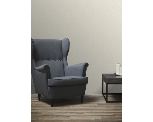 Wohnzimmer mit Sessel, Tisch und gemusterter Tapete für eine gemütliche Atmosphäre.