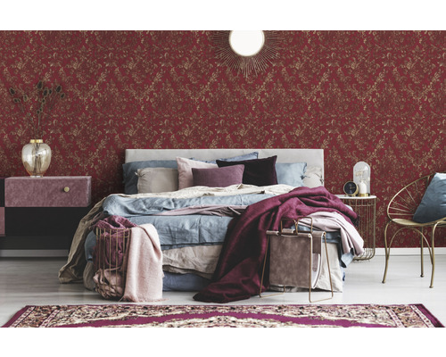 Ein Schlafzimmer mit einem Bett, einem Nachttisch und einer roten Tapete mit Muster