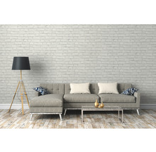 Wohnzimmer mit grauem Sofa, Stehlampe und Couchtisch vor einer Backsteinwand