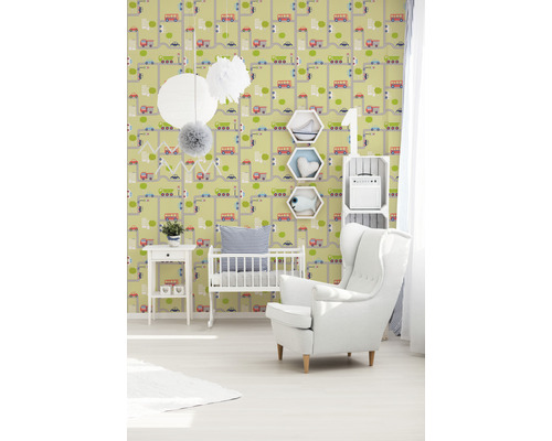 Ein Kinderzimmer mit einer Tapete mit Straßen und Fahrzeugen, einem Kinderbett und einem Sessel.