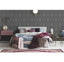 Ein Schlafzimmer mit einem Bett, Nachttischen, einer Lampe und einer gemusterten Tapete