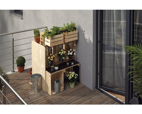 Holzregal mit Kräutern und Blumen auf einem Balkon