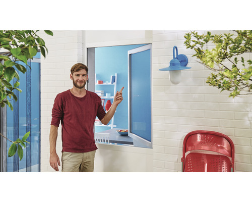 Mann zeigt auf ein Insektenschutzgitterfenster in einem Wohnbereich