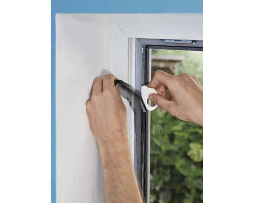 Person befestigt ein Insektenschutzgitter an einem Fensterrahmen mit einem Montagewerkzeug.