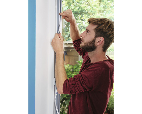 Mann bringt Dichtungsband an Fenster an