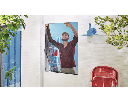 Mann montiert ein Moskitonetz an einem Fenster, um Insekten fernzuhalten.