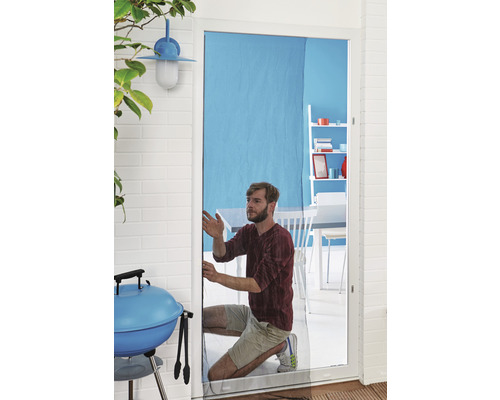 Mann montiert Insektenschutzgitter an einer Tür. Im Hintergrund sind Grill und Gartenmöbel zu sehen.