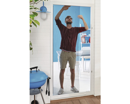 Mann montiert Insektenschutzgitter an einer Terrassentür. Im Hintergrund sind ein Grill und Gartenmöbel zu sehen.