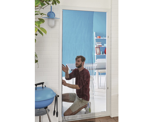 Mann montiert Insektenschutzgitter an einer Terrassentür