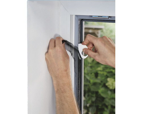 Montage eines Insektenschutzgitters am Fensterrahmen mit Werkzeug.