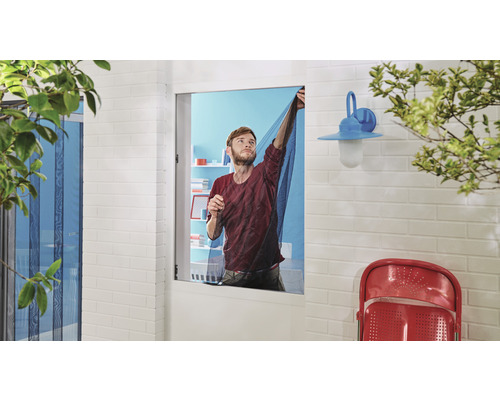 Mann befestigt ein Insektenschutzgitter an einem Fenster.