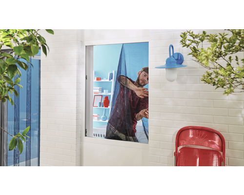 Mann montiert ein Insektenschutzgitter an einem Fenster.