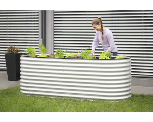 Hochbeet aus Metall mit Bepflanzung und einer Frau, die darin arbeitet