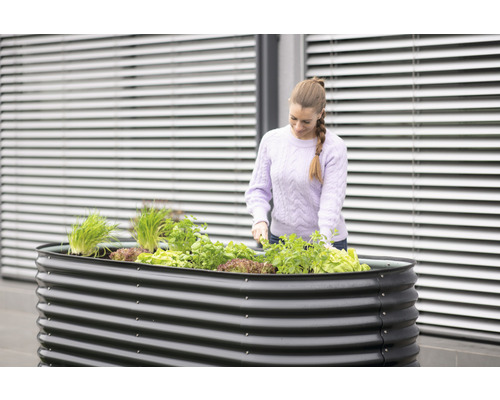 Hochbeet aus Metall mit Pflanzen und Frau bei der Gartenarbeit