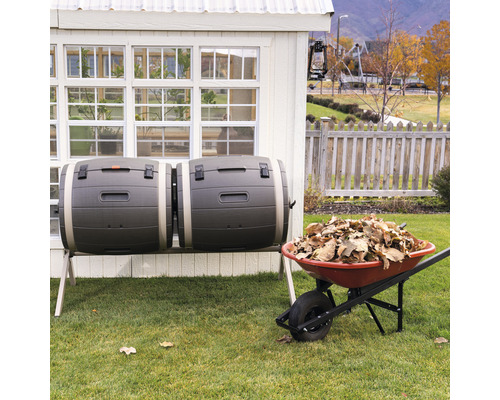 Doppelter Kompostierer neben einer Schubkarre voller Laub im Garten