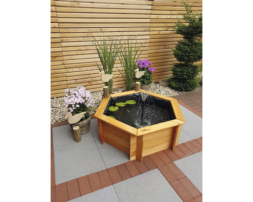 Hexagonaler Holzbrunnen im Garten mit Wasserspiel und Dekoration