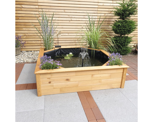 Holzteich mit Wasserspiel, Wasserpflanzen und Uferbepflanzung vor Holzwand