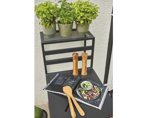 Küchentisch mit Kräutern, Kochbuch, Kochlöffeln und Gewürzmühlen