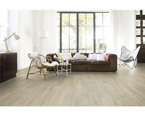 Heller Wohnraum mit braunem Sofa, Rattansessel und Holzfußboden