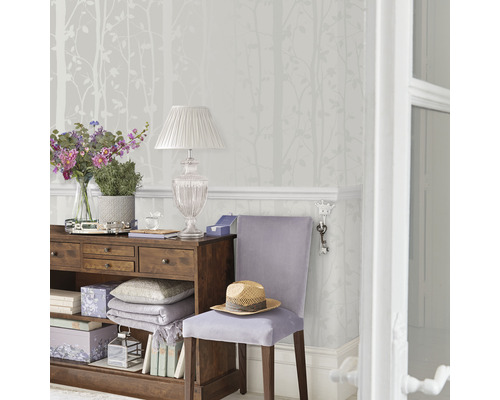 Dekoratives Zimmer mit Kommode, Lampe und Tapete mit Baummotiv