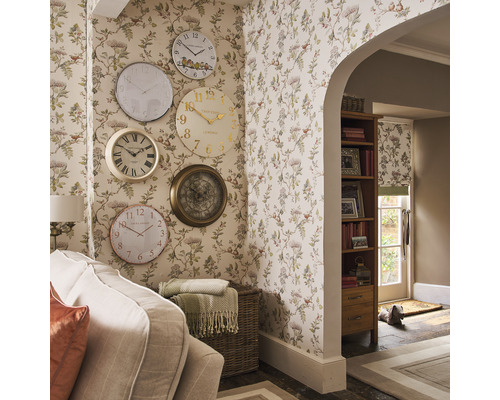 Wohnraum mit floraler Tapete und einer Sammlung von Wanduhren in verschiedenen Designs