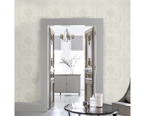 Helles Wohnzimmer mit floral gemusterter Tapete und Blick durch eine geöffnete Tür.