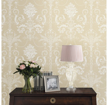 Dekorative Tapete mit Blumenmuster und Kommode mit Lampe, Blumenstrauß, Bilderrahmen und Büchern