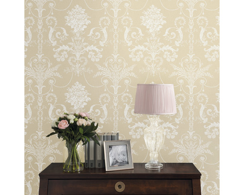 Dekorative Tapete mit Blumenmuster und Kommode mit Lampe, Blumenstrauß, Bilderrahmen und Büchern