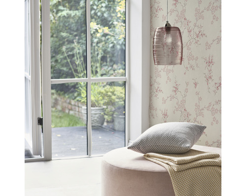 Wohnraum mit floraler Tapete, Pendelleuchte, Kissen und Hocker