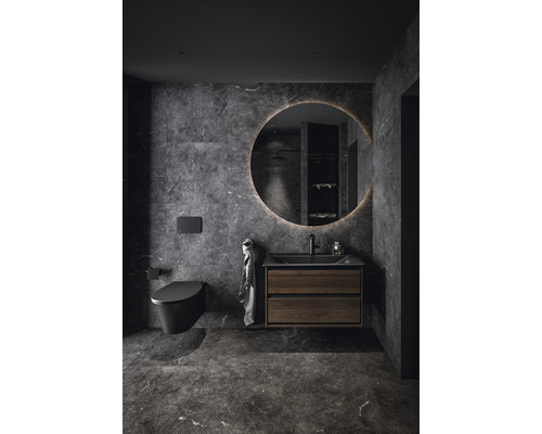 Modernes Badezimmer mit Toilette, Waschtischunterschrank und rundem Spiegel mit Beleuchtung.
