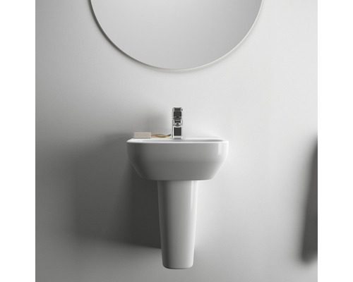 Waschtisch mit Waschtischsäule, Armatur, Seife und Spiegel in hellem Badezimmer.