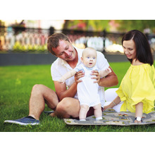 Familie mit Baby auf einer Spielmatte im Freien.